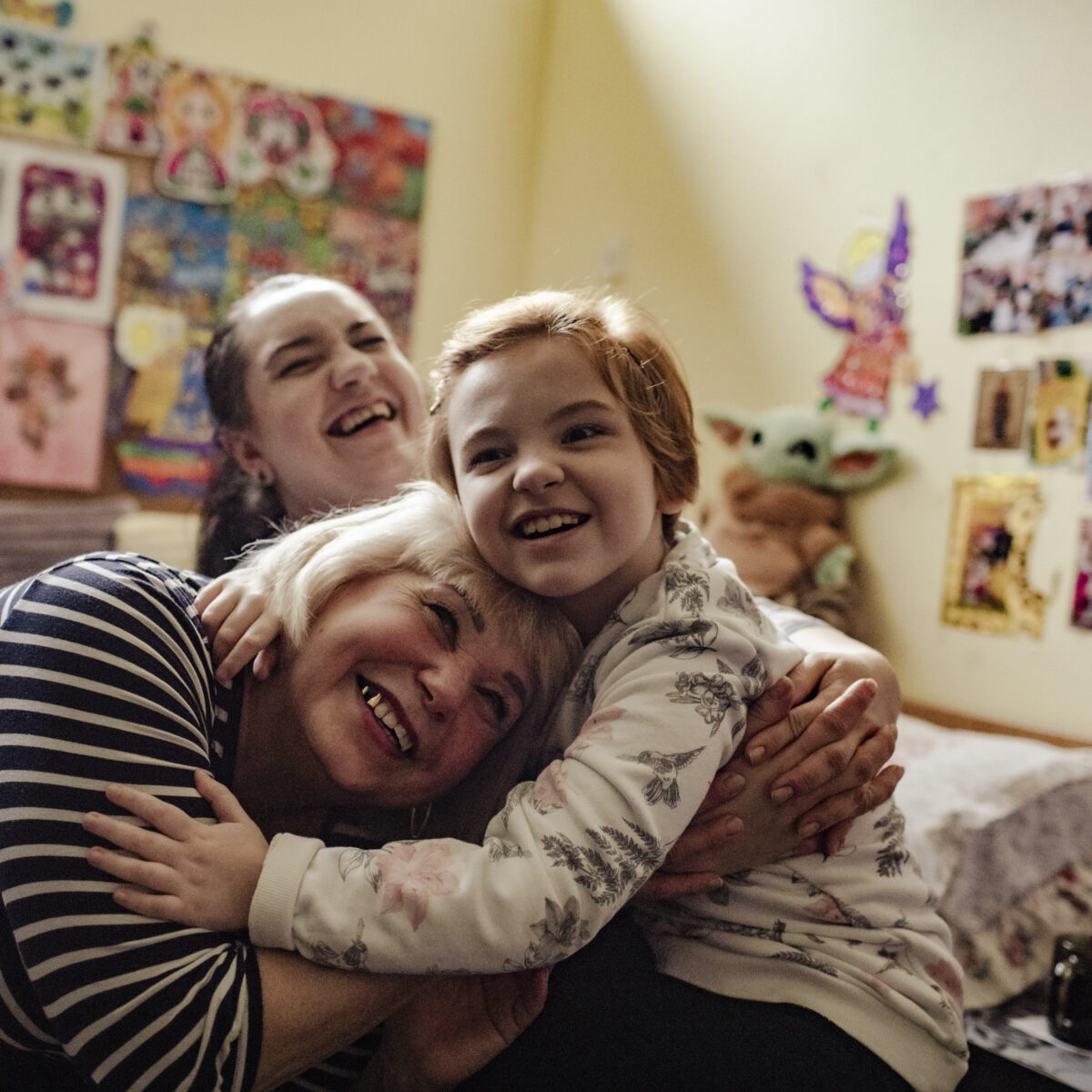 Nadia (61), her daughter Yuliia (38) and Alisa (8) pictured in their one room accommodation at a collective centre in Dnipro. The family hails from Luhansk Oblast. Life before the full-scale invasion was easy in comparison to the challenges now faced by this three-generation family. Alisa, who has special needs, and her mother lived in a specially designed home to accommodate Alisa’s physical disability. However, the family would soon be displaced as hostilities drew near their village. Explosions could be heard nearby and the family sought safety in a single room in the house. They used pillows to drown out the sound of explosions and told Alisa that the loud explosions were thunder nearby. On 2 March, shelling damaged their home and that of their neighbours. Following the incident, they stayed indoors for a full month, in fear for their lives. The family then decided to find safety in Dnipro and took private transport as there were no seats available for children with special needs. As they drove through the countryside away from their village, they were shocked by the scale of damaged and destroyed houses on the route. ; The collective site hosts some 65 people in total. Yuliia and her family had little to no belongings when they arrived at the collective site; just one suitcase and a children’s wheelchair. Locals donated bedsheets, towels, children’s diapers and other items to the family to help. UNHCR’s local partner, Proliska, developed a child-friendly space at the centre, and host activities for children on a regular basis. Alisa has made lots of new friends and a child psychologist is helping her manage her stress through play.
